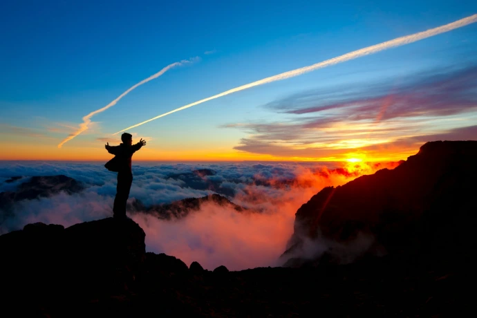 a man standing on top of a mountain at sunset